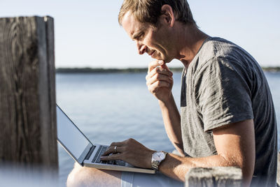 Profile shot of mature man using laptop on pier