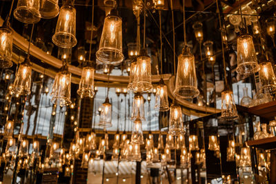 Low angle view of illuminated light bulbs hanging in glass