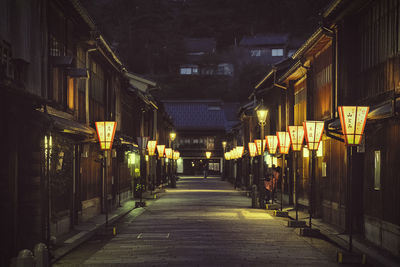 Alley amidst illuminated city at night