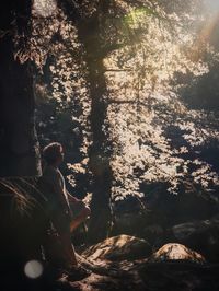 Man sitting on rock in forest