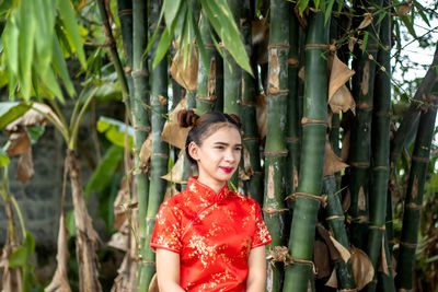 Portrait of smiling young woman standing by tree