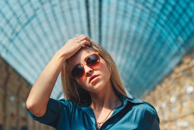 Portrait of young woman wearing sunglasses against ceiling