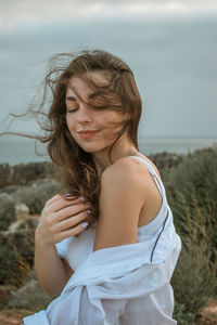 Beautiful woman with eyes closed standing against sky