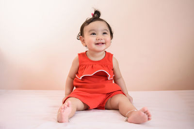 Portrait of cute smiling girl sitting on bed