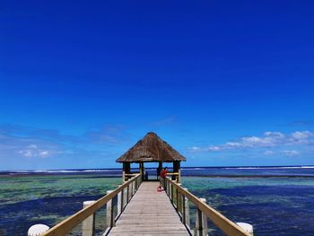 Pier over sea against blue sky