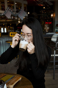 Young woman drinking coffee at sidewalk cafe