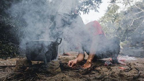 Young man cooking food in forest