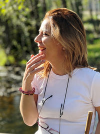 Side view of young woman drinking wine in park