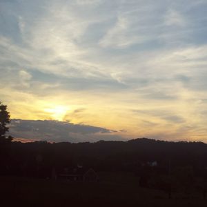 Scenic view of mountains against cloudy sky at sunset