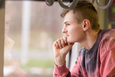 Side view of young man traveling by train, looks out of the window. blond man enjoying a train trip.