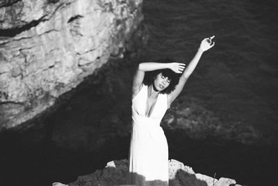 Young woman standing by sea on rock