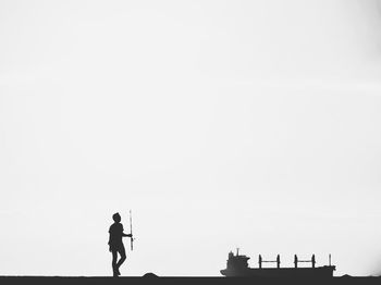 Silhouette man standing on building against clear sky