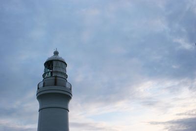 Low angle view of lighthouse by building against sky