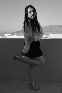 Portrait of woman standing against retaining wall