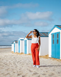 Rear view of woman standing at beach against sky