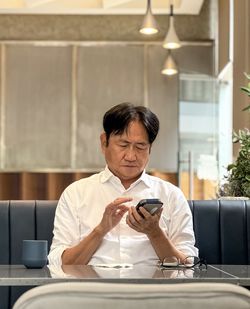 Side view of man using mobile phone while sitting in car