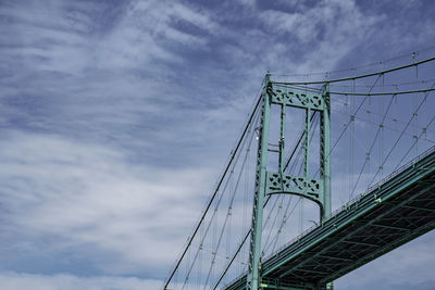 Low angle view of suspension bridge against cloudy sky