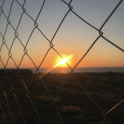 Fence on field against sky during sunset