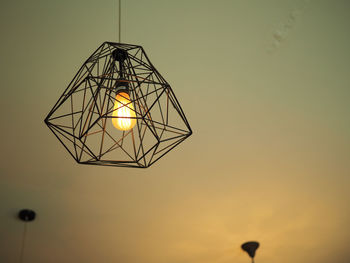 Low angle view of illuminated light bulb against sky during sunset