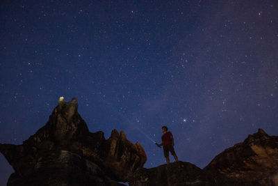 Man standing on rock against sky at night