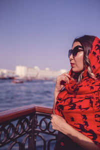 Close-up of young woman standing by railing against lake