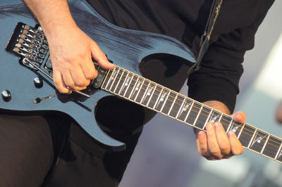 Midsection of man playing guitar