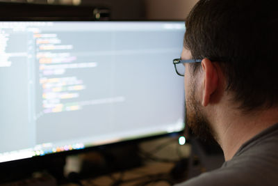 An over the shoulder view of a software engineer in a home environment debugging code.