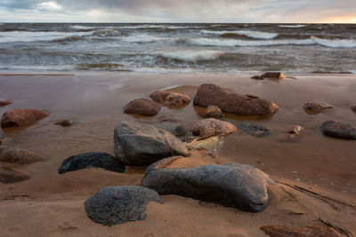 Rocks on beach against sky during sunset