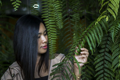 Portrait of young woman looking at tree