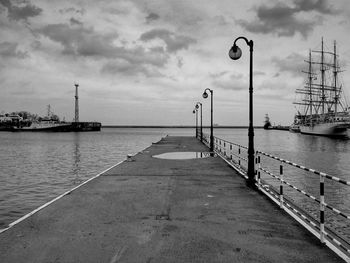 Pier on calm sea against cloudy sky