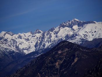 Scenic view of snowcapped mountains against blue sky