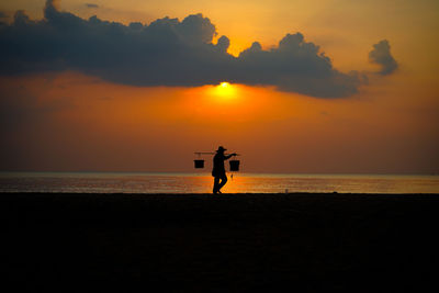 Silhouette man on beach against sky during sunset