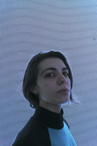 Portrait of young woman looking away against wall