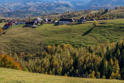 Scenic view of field by houses against mountains