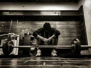 Tired man sitting in front of barbell at gym