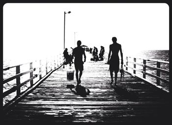 Man walking on pier at sea