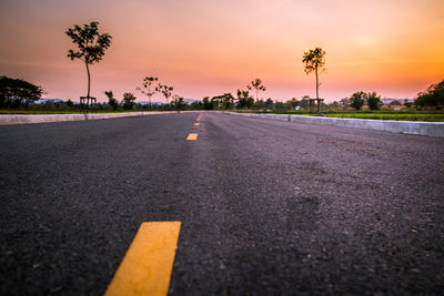 Surface level of road against sky at sunset