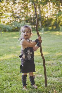 Cute baby dressed in the clothes of primitive people with combat staff