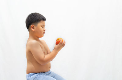 Boy holding apple against white background