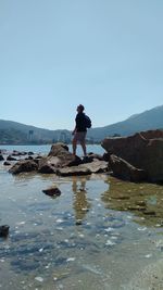 Man standing on rock against sky