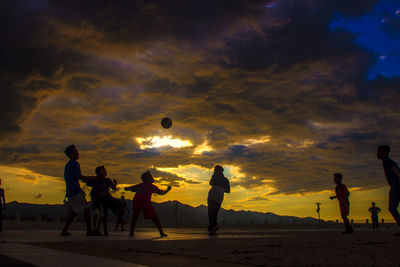 Silhouette people against dramatic sky during sunset