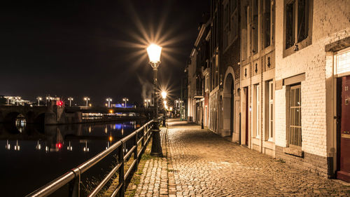 Illuminated street amidst buildings at night