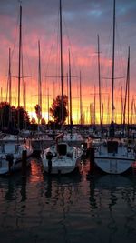 Boats moored at harbor during sunset