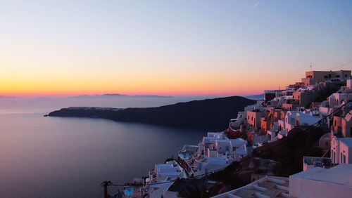 Town by sea against sky during sunset