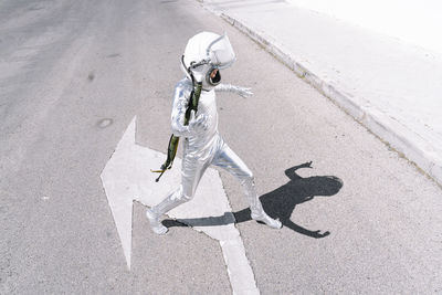 Boy wearing astronaut costume walking on road in city