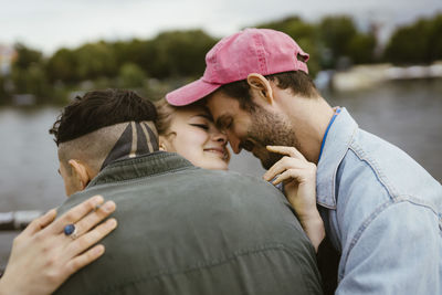 Smiling non-binary person embracing friends