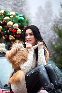 Portrait of woman sitting on car during winter