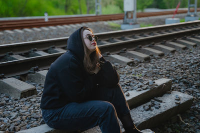 Young woman sitting on railroad track