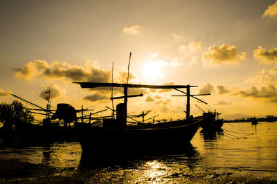 Silhouette boat in sea against sky during sunset