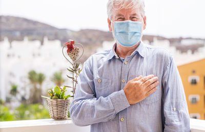 Portrait of senior man wearing mask standing outdoors